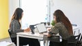 Two of young hardworking female working at office with electronic devices, using laptop