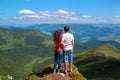 Two young hikers standing on top of a mountain and enjoying a beautiful valley view Royalty Free Stock Photo