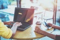 Two young hipster girl hands using on her laptop and smart phone sitting at wooden table in a coffee shop. Royalty Free Stock Photo