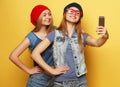 Two young hipster girls friends taking selfie over yellow background Royalty Free Stock Photo