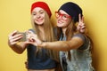 Two young hipster girls friends  taking selfie over yellow background Royalty Free Stock Photo