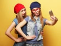 Two young hipster girls friends  taking selfie over yellow background Royalty Free Stock Photo