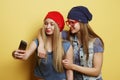 Two young hipster girls friends  taking selfie over yellow background Royalty Free Stock Photo