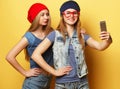 Two young hipster girls friends  taking selfie over yellow background Royalty Free Stock Photo