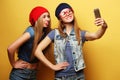 Two young hipster girls friends taking selfie over yellow background Royalty Free Stock Photo