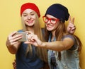 Two young hipster girls friends taking selfie over yellow background Royalty Free Stock Photo