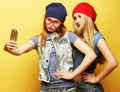 Two young hipster girls friends taking selfie over yellow background Royalty Free Stock Photo