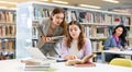 Two young interested women using laptop and books in library