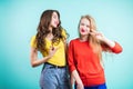 Two young joyful women on blue background. Youth, happiness, fashion, friendshi.