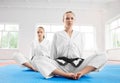 Two young karate girl sittting in lotus position after training in light gym.