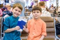 Two young kids sitting on brown chairs, holding passports and tickets in waiting hall in airport. Travel and holidays with Royalty Free Stock Photo