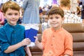 Two young kids sitting on brown chairs, holding passports and tickets in waiting hall in airport. Travel and holidays with Royalty Free Stock Photo