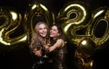 Two young ladies drinking champagne. Image of girls with balloons isolated on black background Royalty Free Stock Photo