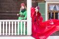 Two Young Ladies in Fashionable Unique Dresses With Kokoshnik Posing Against Old Wooden House in Winter Outdoors Royalty Free Stock Photo