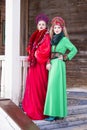 Two Young Ladies in Fashionable Unique Dresses With Kokoshnik Posing Against Old Wooden House in Winter Outdoors Royalty Free Stock Photo