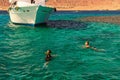 Two young ladies are snorkeling in clean water over reef near the moored yacht. Travel and tourism concept. Red Sea, Dahab, Egypt