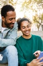 Two young latin american people using smart phone together sitting outdoors Royalty Free Stock Photo