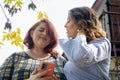 two young latin friends standing talking to each other and using the phone outside at noon Royalty Free Stock Photo