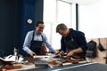 Two young leather craftsmen, joy and joke while working in the workshop, positive leather tailors, have fun at work