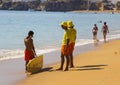 Two young lifeguards chat to a surfer at the waters edge on the beach at Albfueria in Portugal