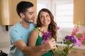 Two young lovers laugh and play in happiness lovingly putting flowers from their garden into a vase Royalty Free Stock Photo