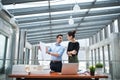 Two young architects with blueprints and model of a house standing in office, talking. Royalty Free Stock Photo