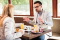 Two young male and female business partners having a meeting over breakfast in a cafe Royalty Free Stock Photo