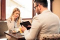 Two young male and female business partners having a meeting over breakfast in a cafe Royalty Free Stock Photo
