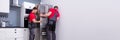 Two Young Male Movers Placing Steel Refrigerator In Kitchen Royalty Free Stock Photo