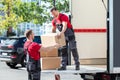 Two Young Male Movers Carrying Cardboard Boxes From Truck Royalty Free Stock Photo