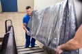 Two Movers Carrying Furniture On Staircase