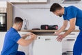 Two movers placing dishwasher in kitchen Royalty Free Stock Photo