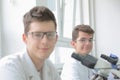 Two Young male scientists looking through a microscope in a laboratory doing research, microbiological analysis, medicine.