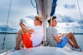 Two young man sitting on a sailboat deck bow adn looking to opposite sides Royalty Free Stock Photo