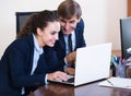 Two young managers using laptop at work