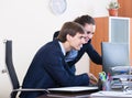 Two young managers using laptop at work