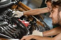 Two young mechanics in green overalls try to fix the engine of a Royalty Free Stock Photo