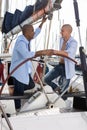 Two young men in blue shirts have a nice time on a private sailing yacht in the seaport