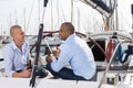 Two men in blue shirts sitting on sailing yacht in the port