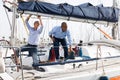 Two young men in blue shirts tidy up private sailing yacht in the seaport