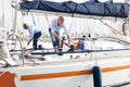 Two young men in blue shirts tidy up private sailing yacht in the seaport