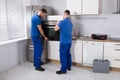 Two Men Fixing Oven In Kitchen Royalty Free Stock Photo