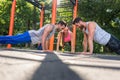 Two young men clapping hands from plank position during partner workout