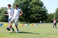 Two Young Men Compete In Three-Legged Race At Summer Fundraiser Royalty Free Stock Photo