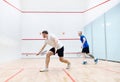 Two young men, friends playing squash together on squash court. Competition and leisure Royalty Free Stock Photo