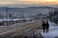 Two men going down the hill along the road along the residential neighborhood and the old wooden buildings in Ulan-Ude.