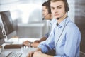 Two young men in headset, sitting at the desk in the modern office, listening to the clients. Call center operators at Royalty Free Stock Photo