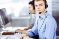Two young men in headset, sitting at the desk in the modern office, listening to the clients. Call center operators at Royalty Free Stock Photo