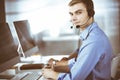 Two young men in headset, sitting at the desk in the modern office, listening to the clients. Call center operators at Royalty Free Stock Photo