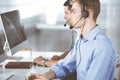 Two young men in headset, sitting at the desk in the modern office, listening to the clients. Call center operators at Royalty Free Stock Photo